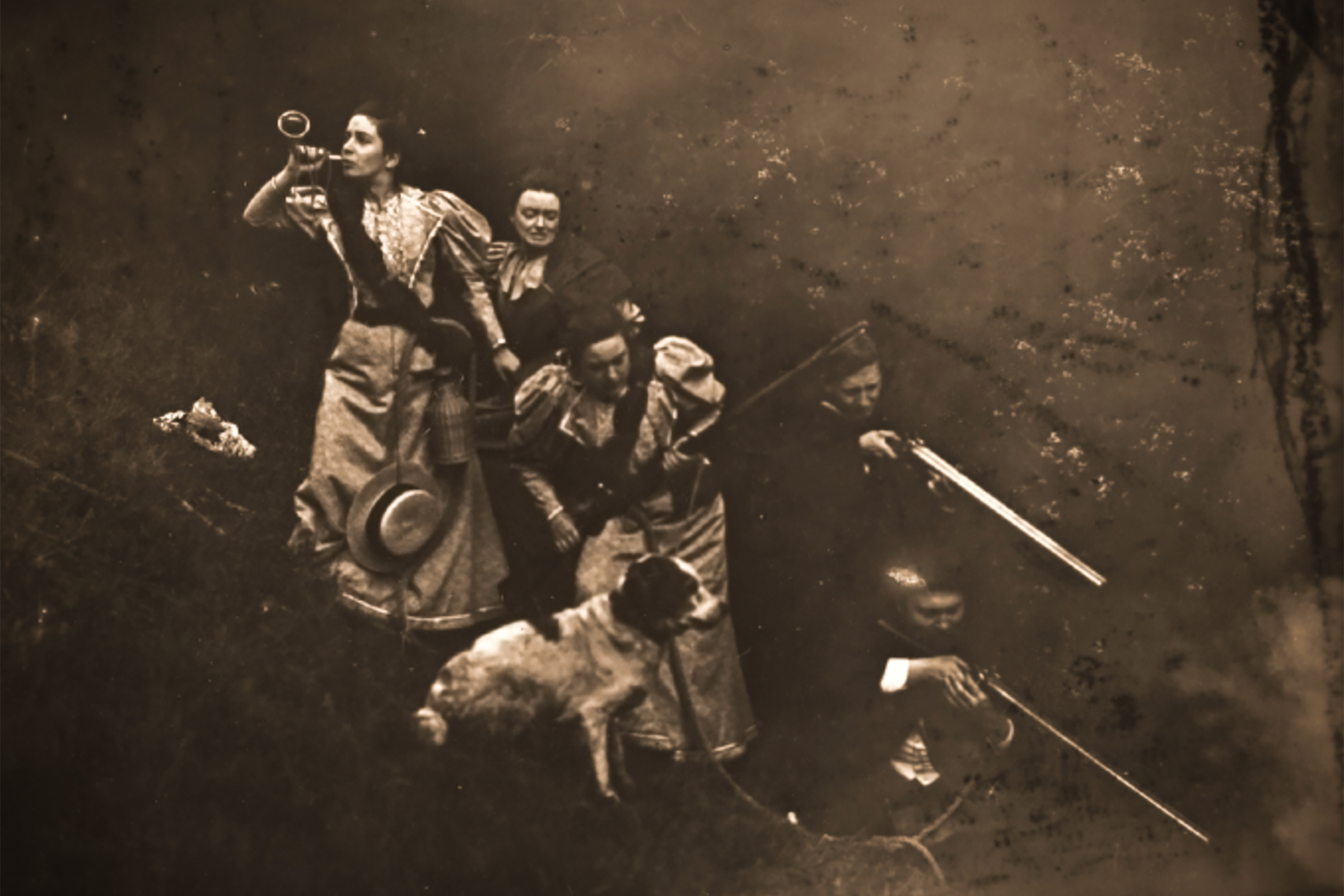 The theatrical expedition party huddles together in a staged forest scene.